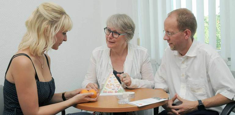 Patienten mit zwei Ärzten im Nachsorgegespräch am Tisch sitzend